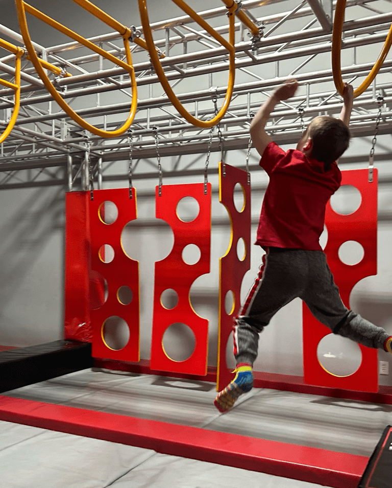 Kid swinging on rings at Go Ninja