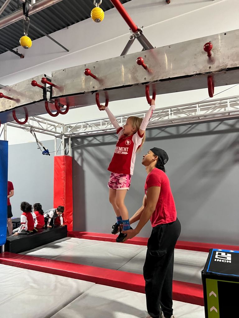 Coach spotting a kid on ring obstacles